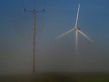 Wind turbines on field against sky