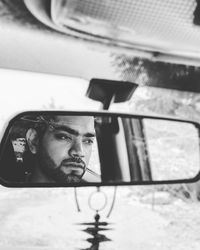 Reflection of man in rear-view mirror