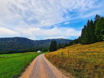 Dirt road along landscape against sky