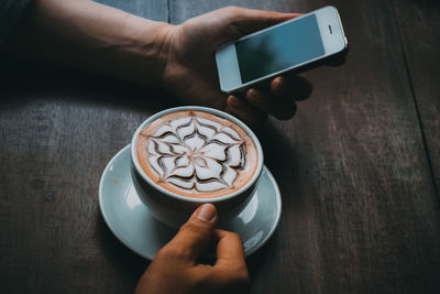 Midsection of person holding coffee cup on table