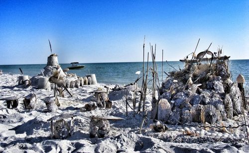 Sandcastle made from seashells at beach against sky