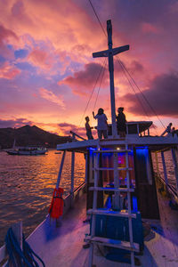 People on pier by sea against sky during sunset