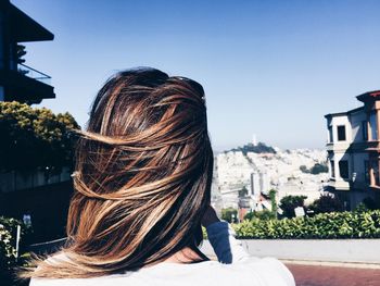 Rear view of woman against sky in city