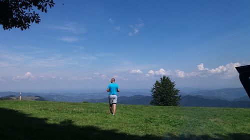 Rear view of man walking on land against sky