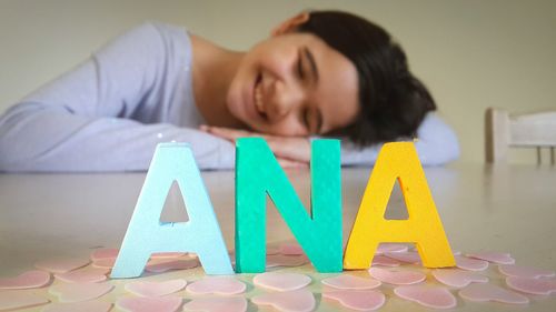 Smiling girl relaxing by alphabets on table at home