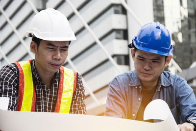 Engineers wearing hardhats while working over blueprints