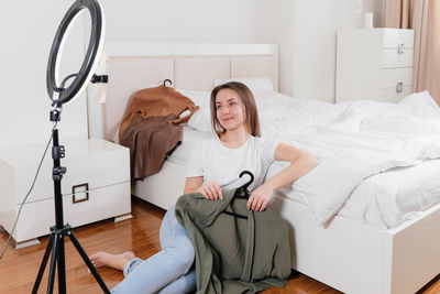 Female blogger recording vlog video on smartphone at home online influencer on near bed choosing