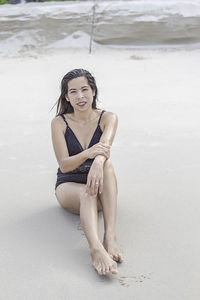 Portrait of a smiling young woman sitting on beach