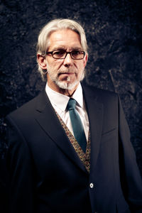 Portrait of man wearing sunglasses standing against black background