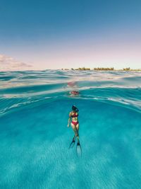 Man surfing in sea against blue sky