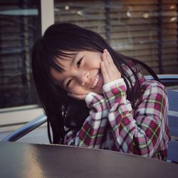 Portrait of cheerful girl sitting at table