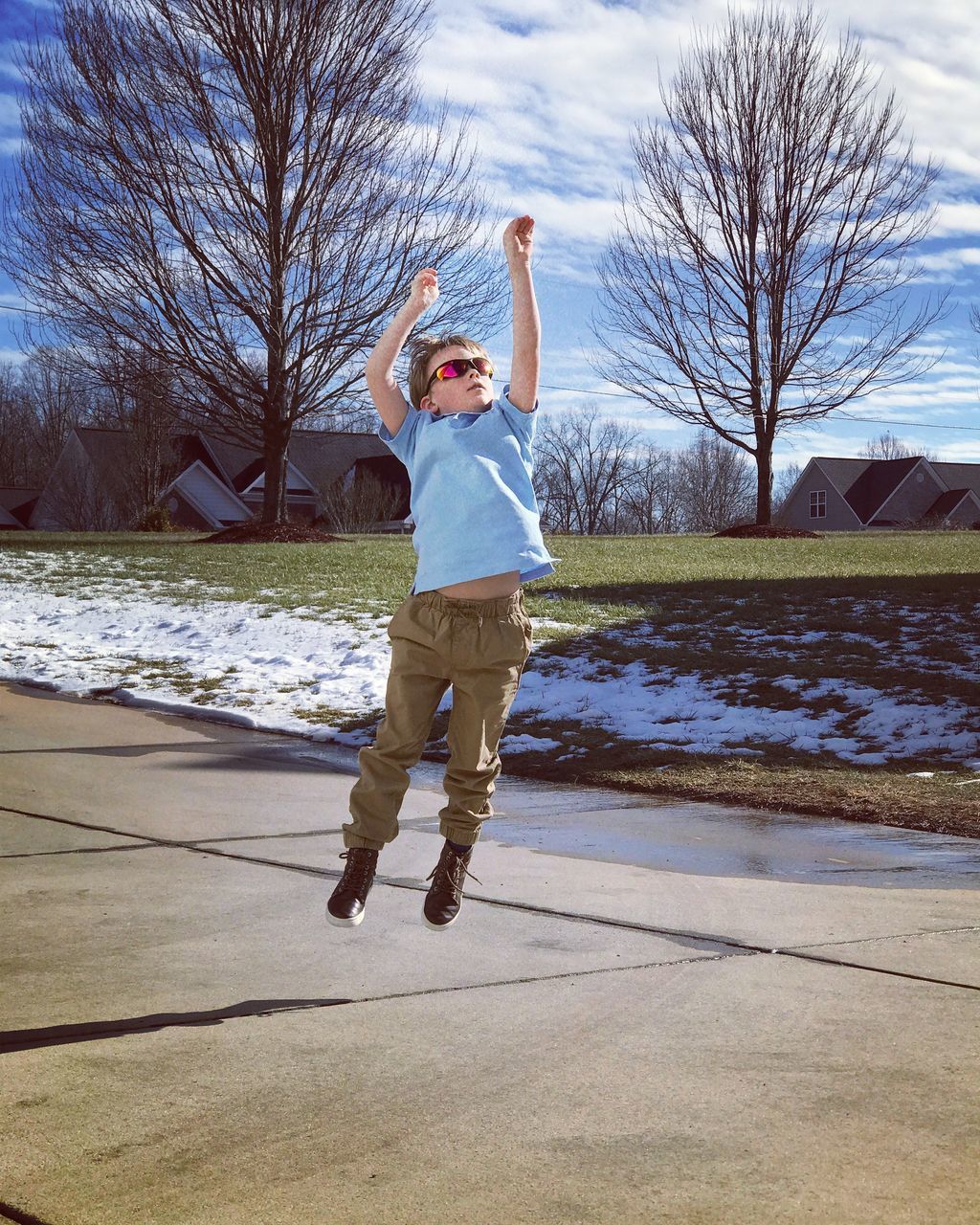 FULL LENGTH OF MAN JUMPING ON BARE TREE AGAINST SKY