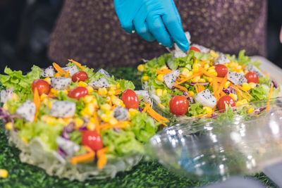 Midsection of person serving salad