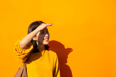 Full length of woman standing against yellow background