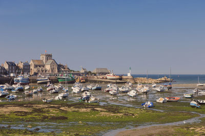 Boats in sea by city against clear sky