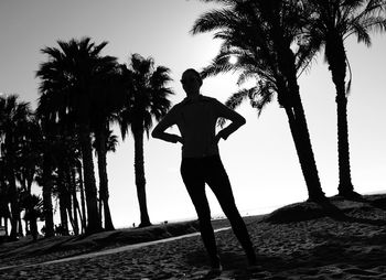 Man standing by palm trees on beach against sky
