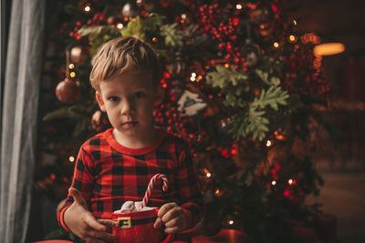 Portrait of cute girl playing with christmas tree at night