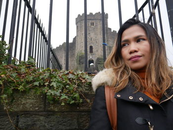 Beautiful young woman standing against building