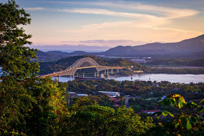 Arch bridge over river against sky during sunset