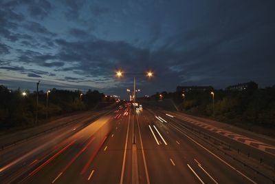 Light trails on highway against sky at dusk