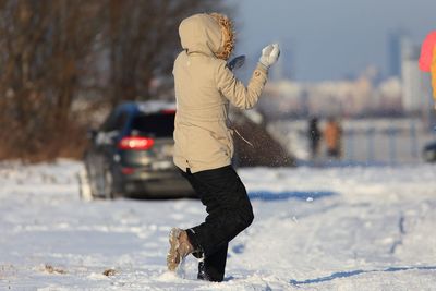 Full length of woman playing on snow during winter