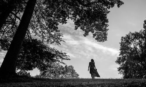 Rear view of woman standing on field against sky