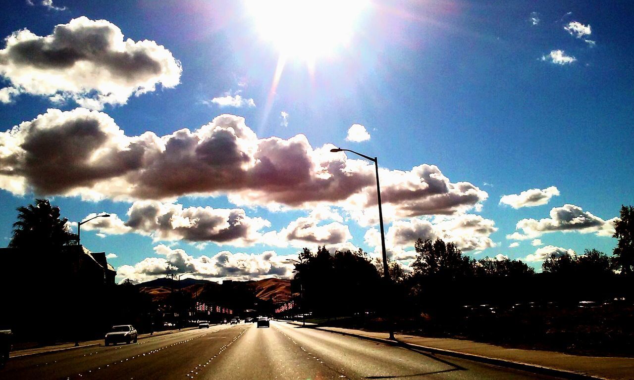 the way forward, sky, road, transportation, cloud - sky, diminishing perspective, vanishing point, road marking, street light, street, tree, cloud, blue, sunlight, car, cloudy, silhouette, sun, nature, empty road