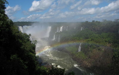 Scenic view of waterfall against rainbow in sky