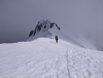 People on snowcapped mountain against sky