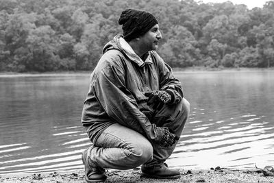 Man sitting by lake against trees