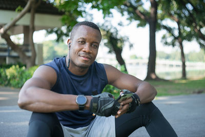 Portrait of young man holding camera while sitting outdoors
