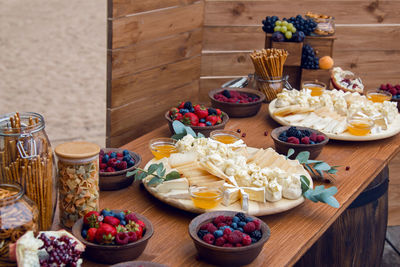 Wooden table with slices of cheese, berries, strawberries, raspberries, blueberries, blackberries