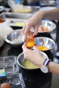 Cropped image of woman hand breaking egg while cooking in kitchen