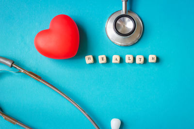 Directly above shot of heart shape with text blocks and stethoscope on blue background