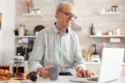 Young man using mobile phone while sitting on table