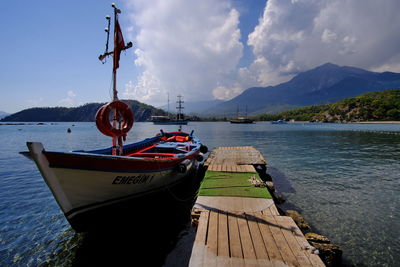 Boat moored by pier on lake against sky