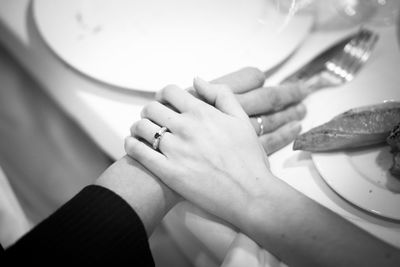 Close-up high angle view of wife touching husband hand at dining table