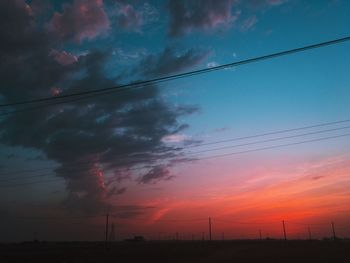 Low angle view of silhouette electricity pylon against sky during sunset