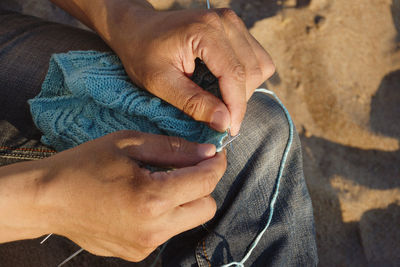 Midsection of man knitting outdoors