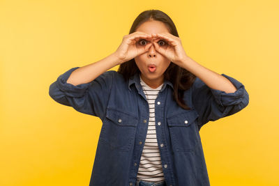 Portrait of beautiful young woman against yellow background