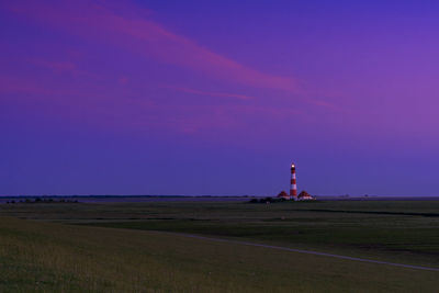 Lighthouse on field against sky at dusk