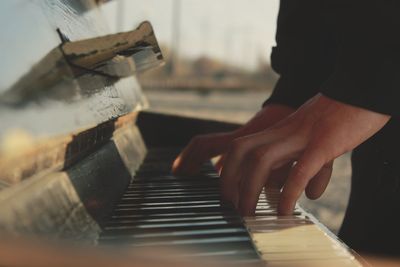 Midsection of men playing piano at home