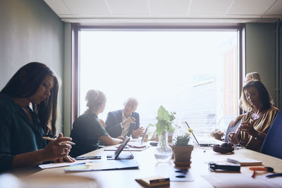 Mature male manager planning strategy with businesswoman by female colleagues in board room