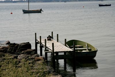 Sailboats moored on pier by sea