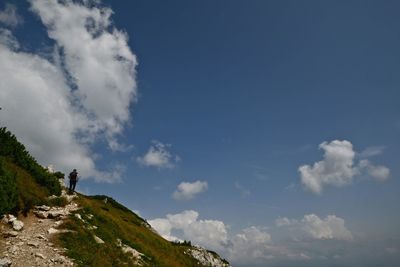 Low angle view of man standing on cliff against sky