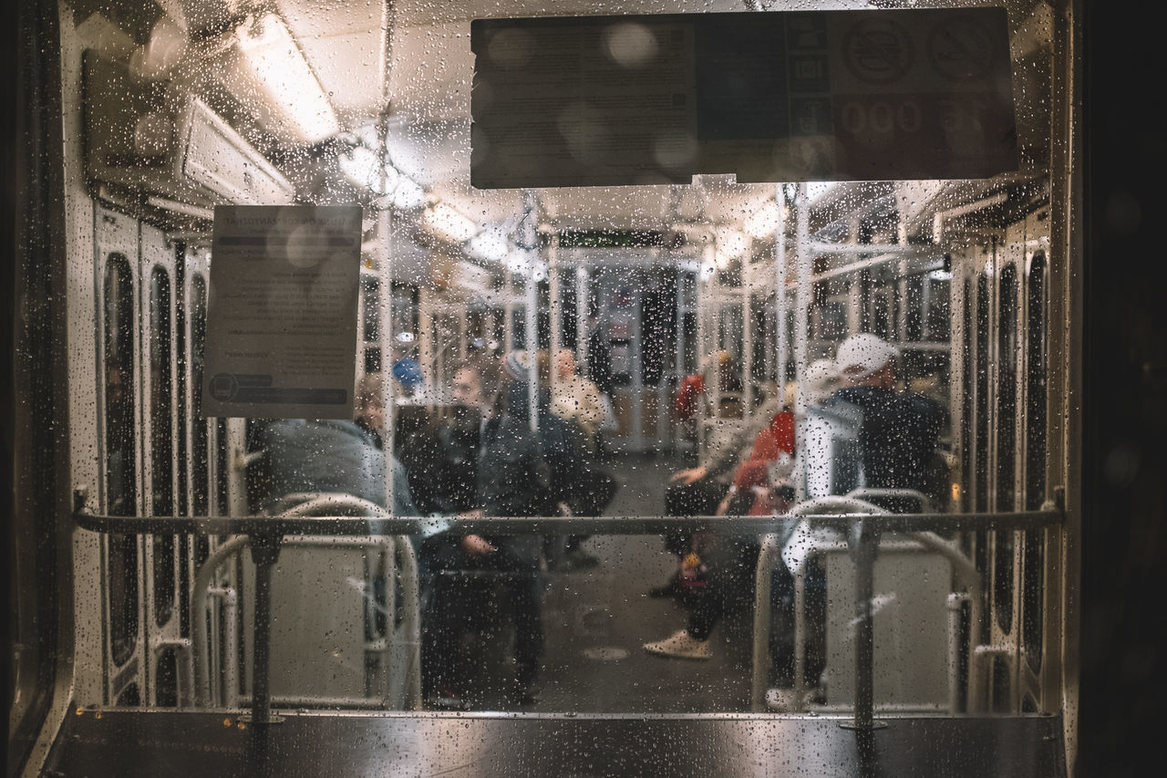 PEOPLE WALKING IN WET GLASS WINDOW IN CITY