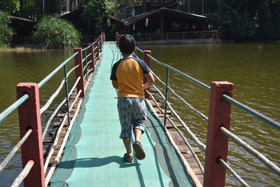 Rear view of man on railing against bridge
