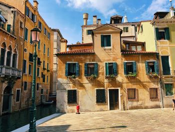 Man walking on street by buildings in city against sky