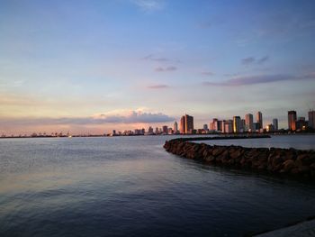 Scenic view of sea and buildings against sky during sunset