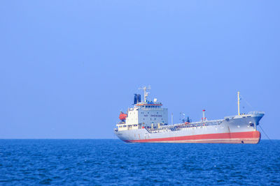 Ship sailing in sea against clear blue sky